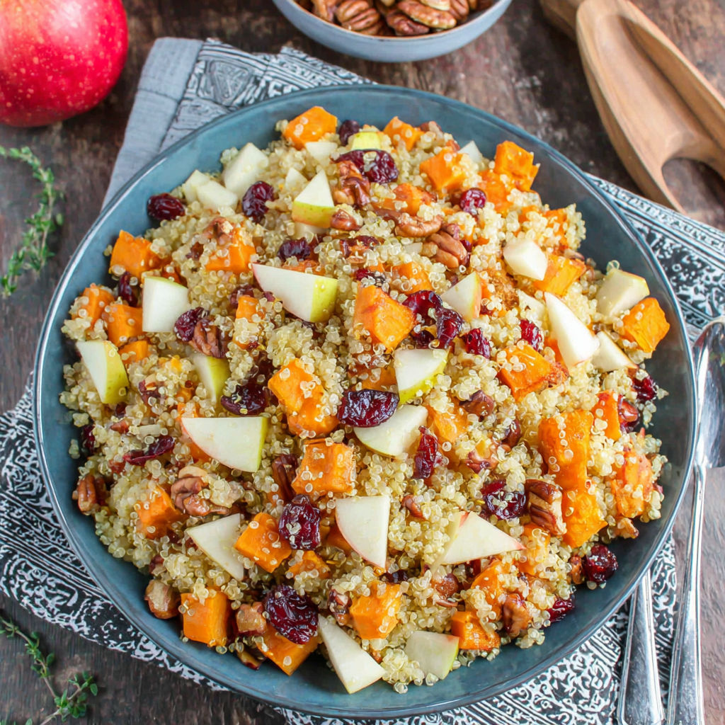 A bowl of food with apples, sweet potatoes, and quinoa.