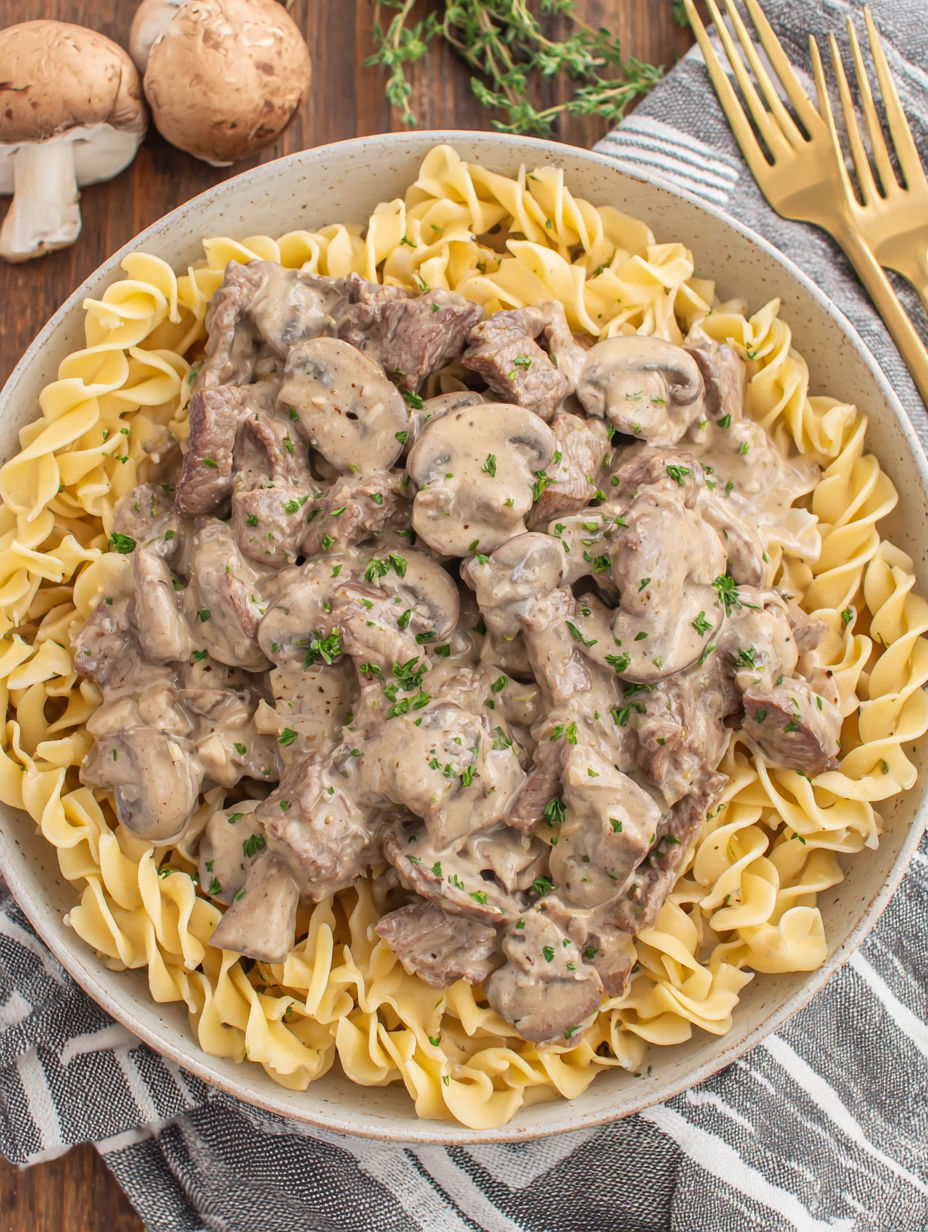 A bowl of pasta with meat and mushrooms.