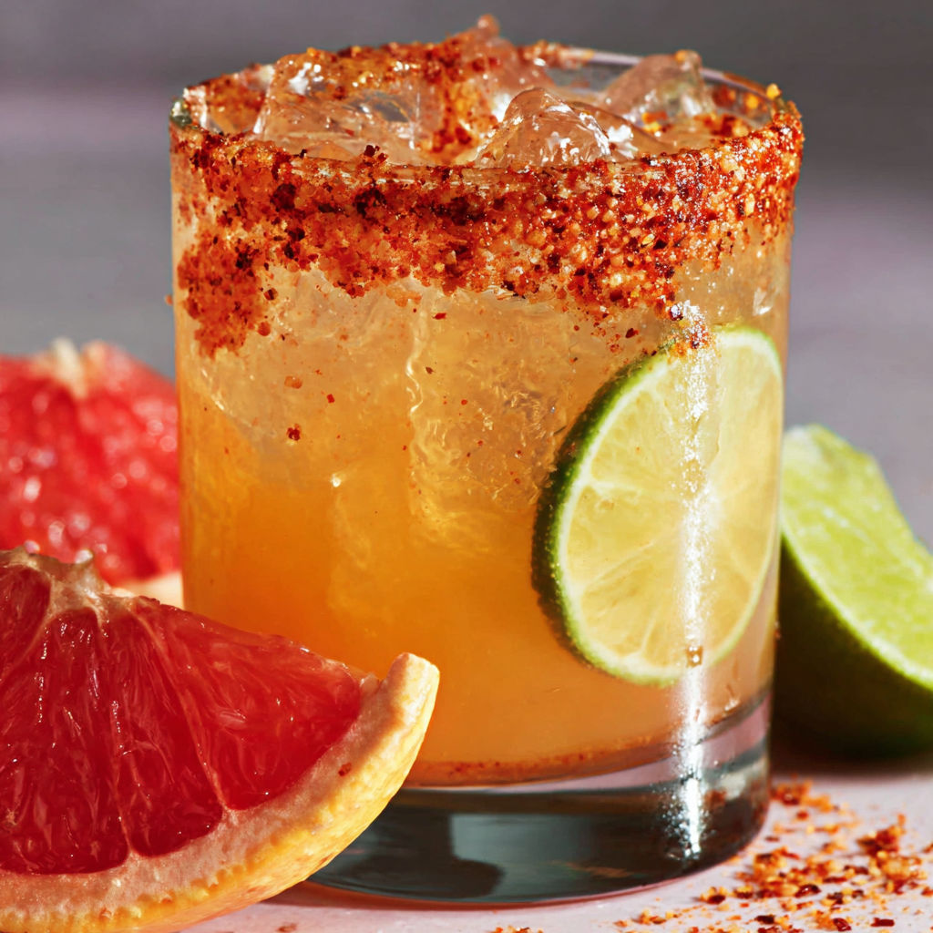 A glass of a spicy paloma cocktail with a slice of grapefruit.