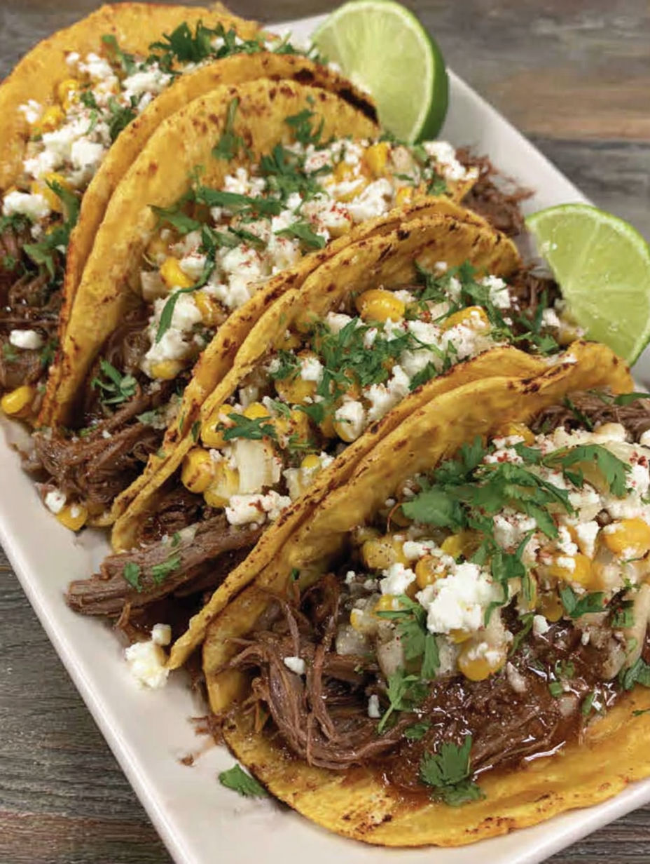 A plate of shredded beef tacos with corn.