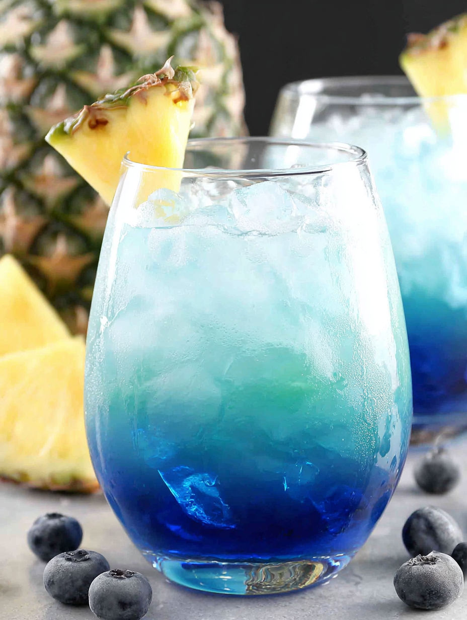A blue drink with a pineapple wedge in it.