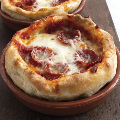 Cheese bubbling in a baked pizza pot pie with pepperoni on top.