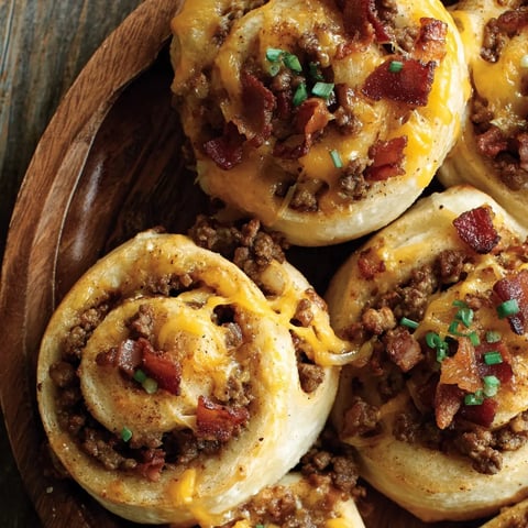 Cheeseburger-filled rolls on a wooden plate.