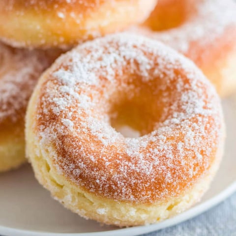 A plate of donuts with powdered sugar on top.