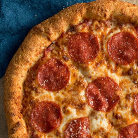 A pizza topped with pepperoni and cheese on a table.