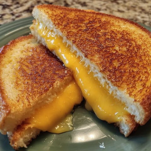Toasted sandwich stuffed with melted cheese on a plate.