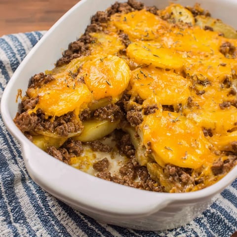 A white bowl with potatoes and beef.