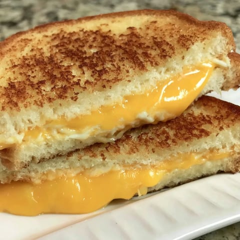 Two melty, golden grilled cheese sandwiches on a plate.