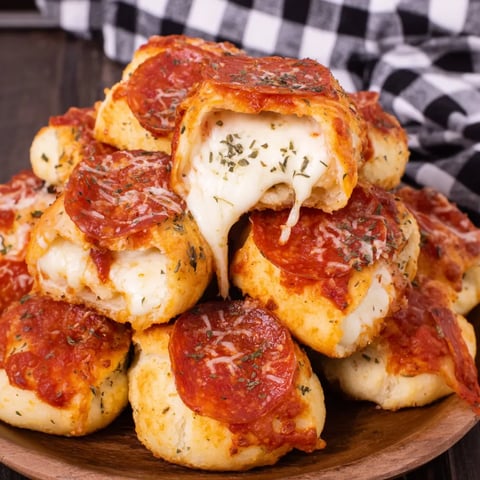 A plate piled with cheesy crust pizza snacks.