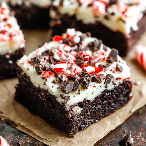 A square of chocolate cake with white frosting and red and white sprinkles.