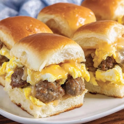 Plate stacked with sausage sliders for breakfast.