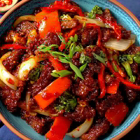 A bowl of beef with peppers and onions.