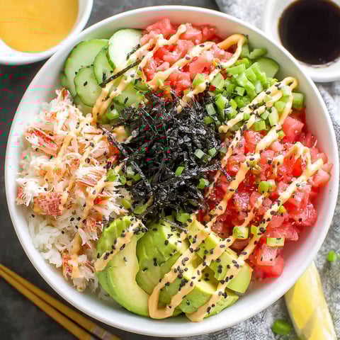 A bowl of sushi with rice, avocado, cucumber, and tomato.