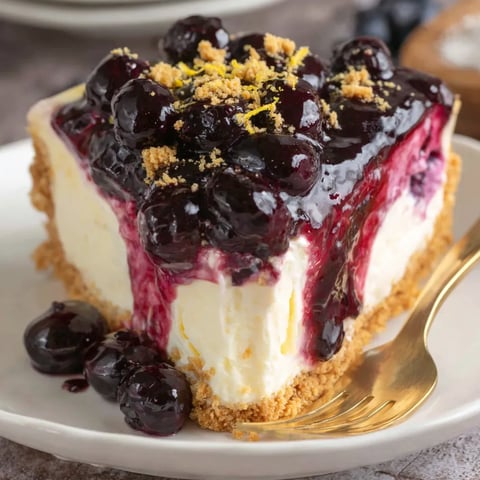 A slice of blueberry cheesecake with a golden spoon.