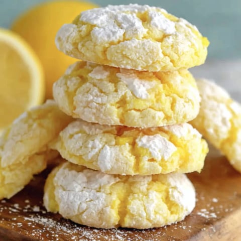 Lemon Cool Whip cookies stacked on a wooden board.