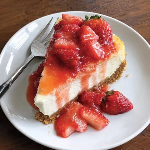 A slice of strawberry cheesecake on a plate.