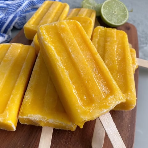 A wooden board with mango margarita popsicles on it.