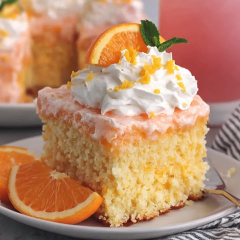 A slice of orange crush cake with orange slices on top.
