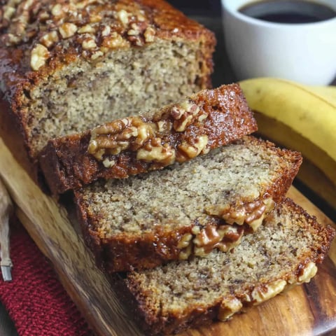 A loaf of banana nut bread with a cup of coffee.