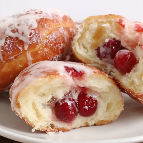 Three doughnuts with cherries and vanilla glaze.