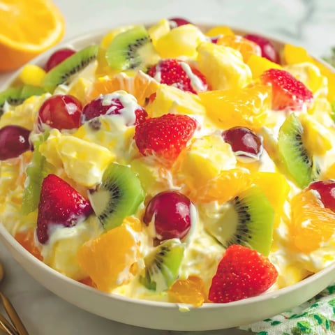 A bowl of fruit salad with kiwi, strawberries, and oranges.