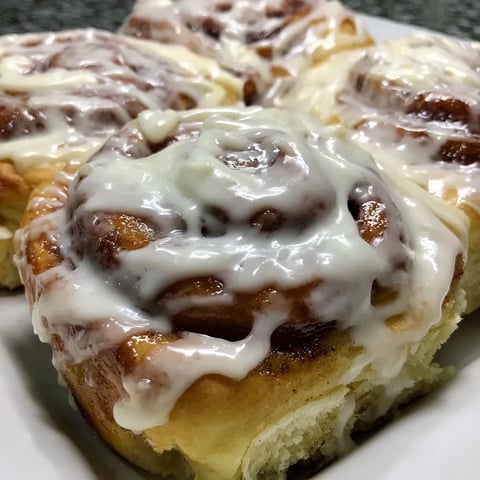 A plate of cinnamon rolls with icing.