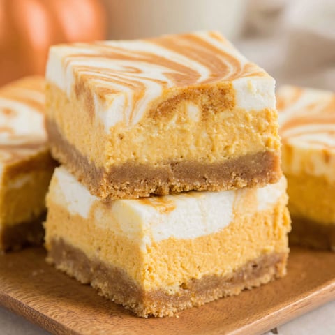 A stack of swirled pumpkin cheesecake bars.
