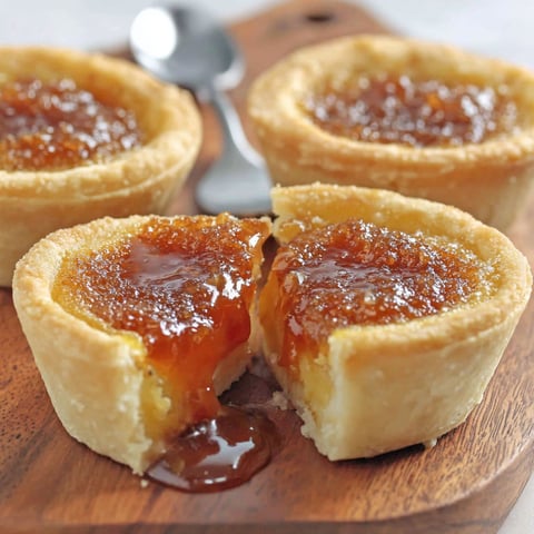 Three pieces of butter tart on a wooden board.