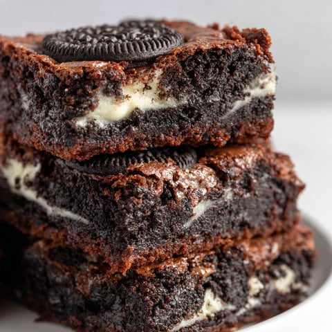 A stack of brownies with Oreo cookies on top.