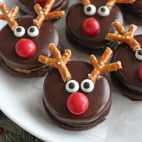 A plate of chocolate cookies with red and white frosting shaped like reindeer.