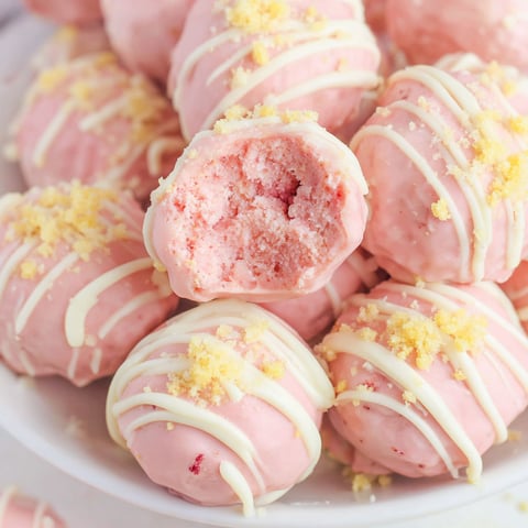 A bowl of pink and white frosted strawberry shortcake truffes.