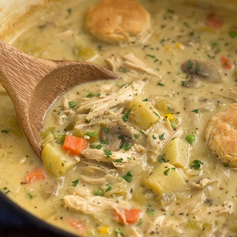 A wooden spoon in a bowl of soup.