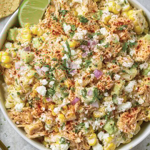A bowl of chicken salad with corn and avocado.