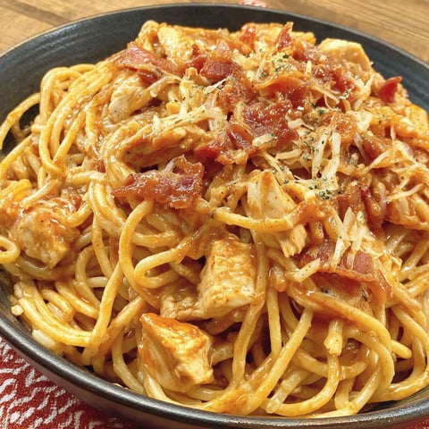 A bowl of spaghetti with chicken and bacon.