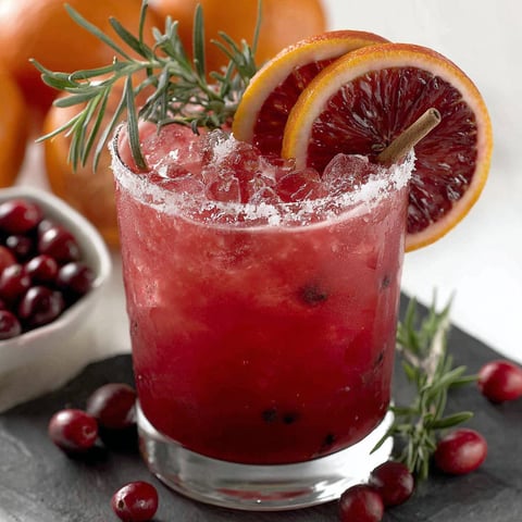 A glass of red cranberry Christmas cocktail.