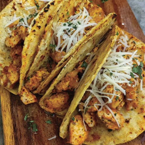 A plate of chicken tacos with cheese.