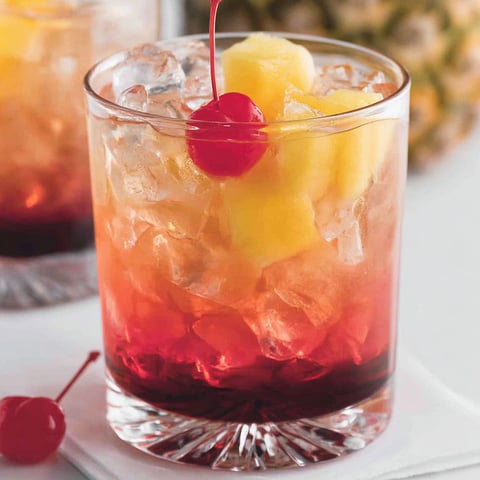 A glass of a campfire cocktail with a cherry on top.