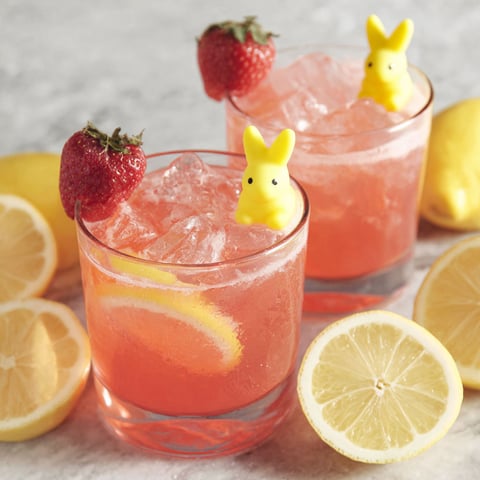 Two glasses of pink drink with bunny ears on top.