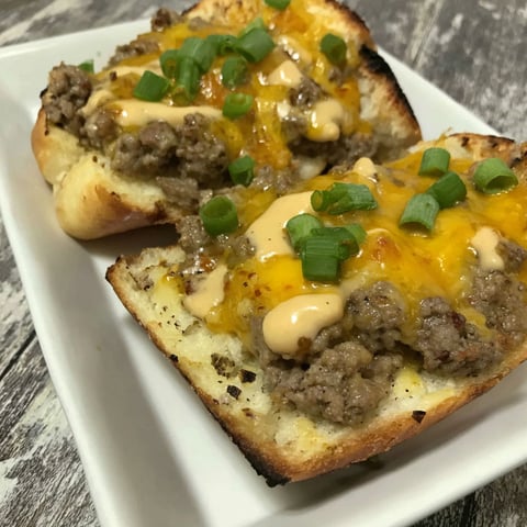 A cheeseburger garlic bread on a white plate.