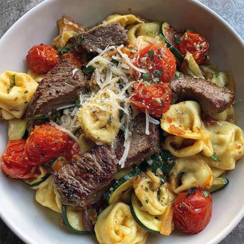 A bowl of food with tomatoes, zucchini, and meat.