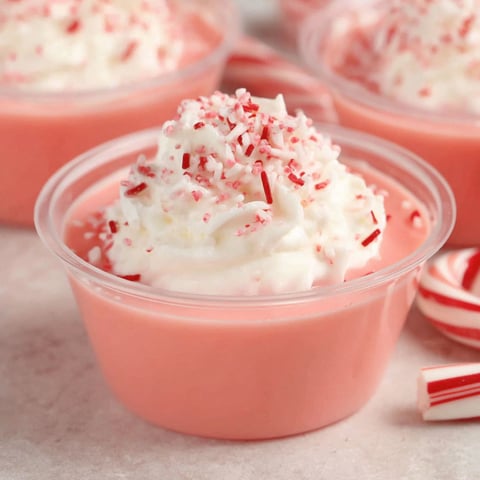 A bowl of pink jello with red and white stripes.