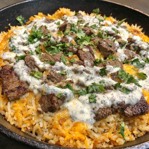 A dish of steak, cheese, and rice.