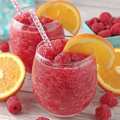 Two glasses of red raspberry orange slushies.